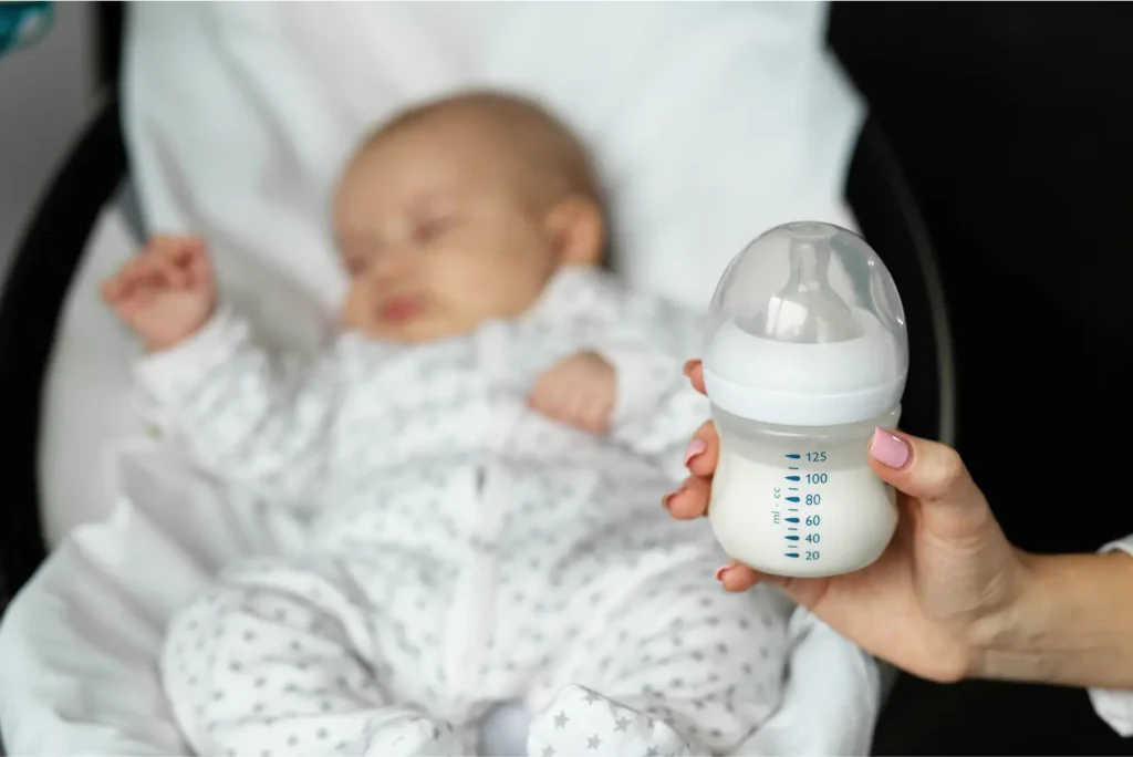 bottle of baby formula milk in mothers hands